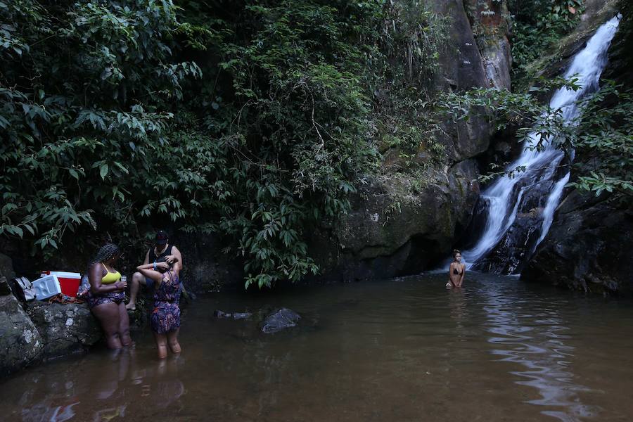 Ya ha comenzado ell verano austral. Pero las playas de Río de Janeiro ya están llenas de bañistas desde hace unas semanas. Y es que el calor aprieta. El martes los termómetros alcanzaron 40,7 grados en la zona oeste de la ciudad, en el que ha sido el día más caluroso en varios años, con una sensación térmica de 45 grados. El mar está calmado y apenas hay olas en las transparentes aguas. Las imágenes han sido tomadas en la Floresta de Tijuca, el bosque urbano más grande del mundo, y en los arenales del oeste de Río.