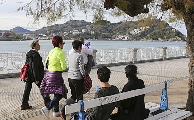 Paseantes en La Concha con las prendas de abrigo en las manos o en la cintura