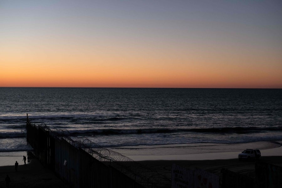 La gente camina cerca de la valla fronteriza entre México y Estados Unidos en Playas de Tijuana, México. El presidente Donald Trump advirtió el miércoles pasado que el gobierno federal de los EE. UU. se mantiene firme en su deseo de reforzar el muro fronterizo con México.