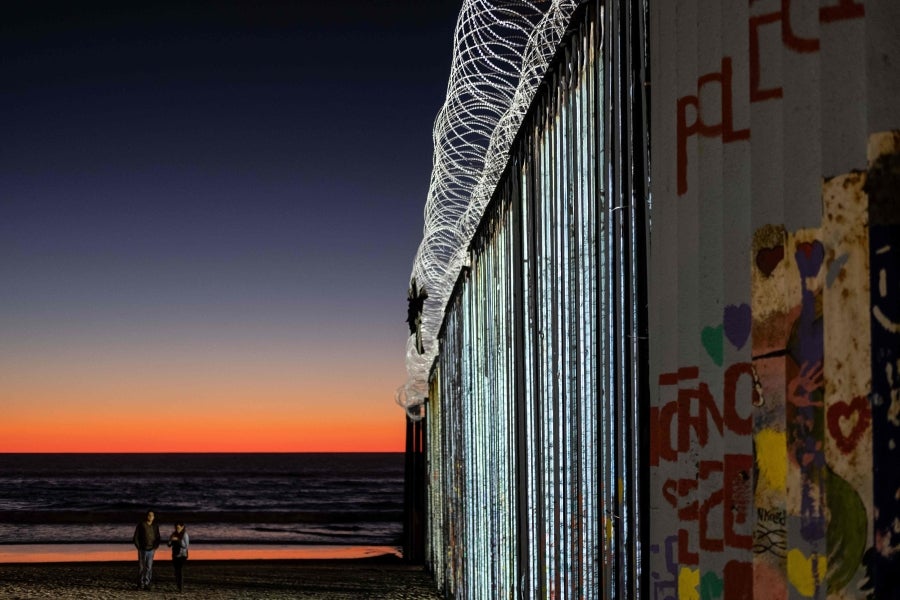 La gente camina cerca de la valla fronteriza entre México y Estados Unidos en Playas de Tijuana, México. El presidente Donald Trump advirtió el miércoles pasado que el gobierno federal de los EE. UU. se mantiene firme en su deseo de reforzar el muro fronterizo con México.