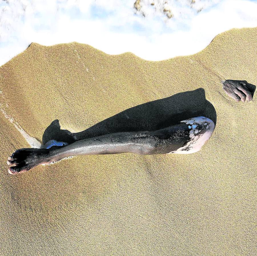 El cadáver de un inmigrante enterrado en la arena en la costa de Karboli, al este de Trípoli, en el verano de 2015