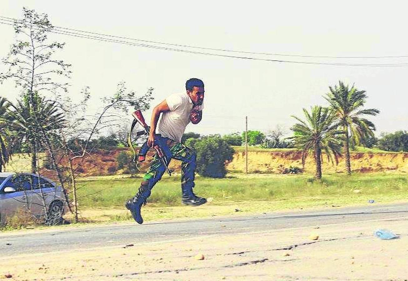 Un combatiente sortea el fuego enemigo en los enfrentamientos entre partidarios de Gadafi y enemigos del régimen, en 2011.