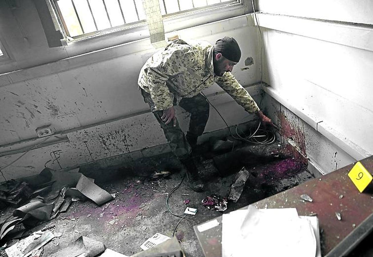 Un soldado señala la mancha de sangre de una víctima de un ataque suicida en una oficina electoral, el 2 de mayo de 2018.