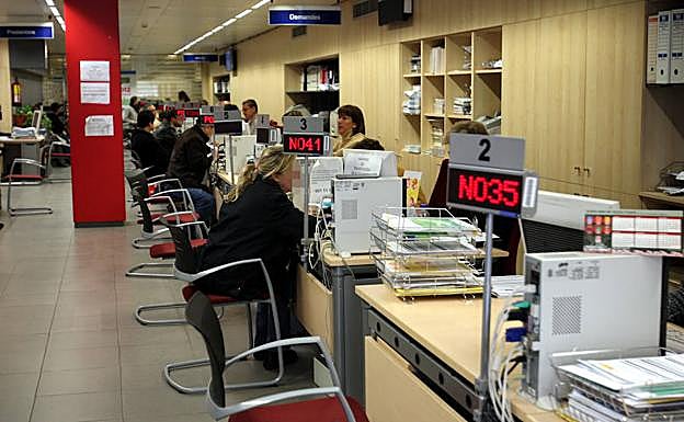 Un grupo de parados realiza trámites en una oficina de empleo.