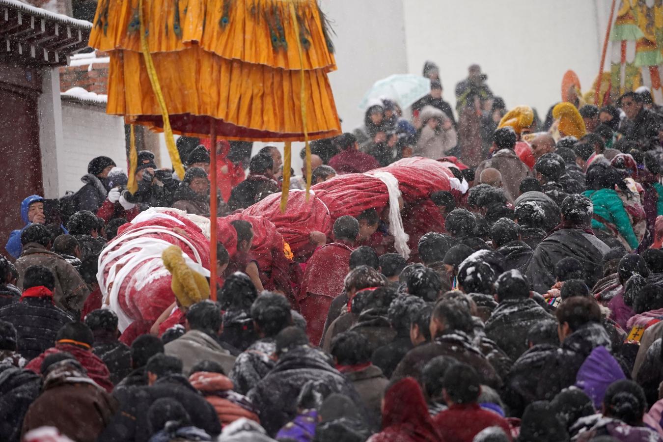 El frío y la nieve no impidió que los monjes tibetanos asistieran a una ceremonia en el Langmu Lamasery durante el 'Sunbathing Buddha Festival', el pasado domingo en la Prefectura Autónoma Tibetana de Gannan, provincia de Gansu, China.