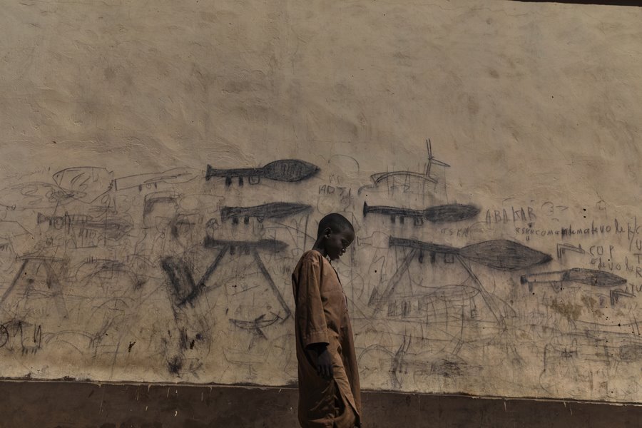 Almajiri Boy. Finalista World Press Photo del año.- Un niño huérfano pasa junto a una pared con dibujos que muestran granadas propulsadas por cohetes en el país africano Chad, donde sufren una crisis que combina factores políticos y ambientales.
