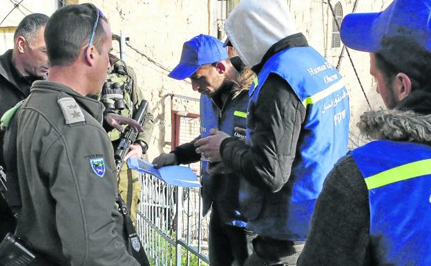 Soldados israelíes piden documentación a los 'chalecos azules' palestinos que quieren llenar el vacío dejado por los observadores internacionales expulsados. 