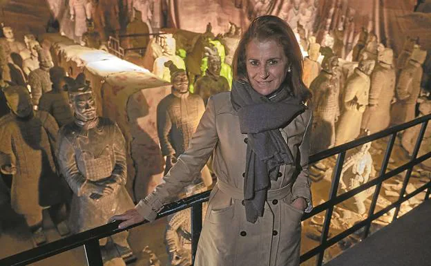 María José Fernández posa ante la reproducción de una parte del foso del yacimiento con 65 soldados que se puede ver en la exposició