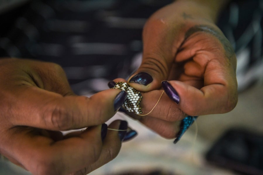 La colombiana Roxana Panchi Gutiérrez, una joven transexual indígena de 24 años, se reúne con sus dos amigas de toda la vida, en el pueblo indígena Cristiania, departamento de Antioquia, para crear accesorios con cuentas. Las mismas cuentas que iluminan las últimas creaciones de la diseñadora colombiana Laura Laurens, cuyos diseños viajan desde Bogotá a Londres, París y Nueva York.