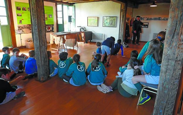 Angel Alberdi, miembro de Lantxabe, explica la historia de Aiete a los escolares, ante una foto antigua, en el aula didáctica de Katxola.