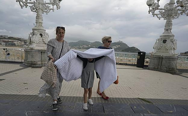 Una niña se protege de la lluvia en el paseo de La Concha.