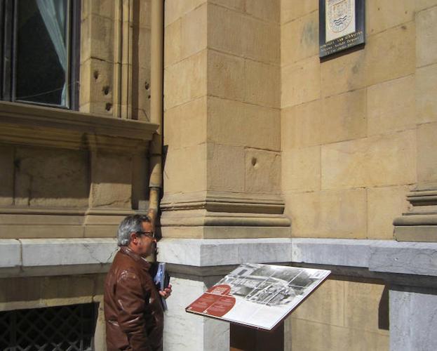 Un hombre lee el panel informativo junto al ayuntamiento.