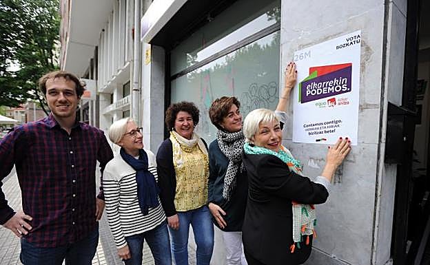María Valiente, junto a miembros de la coalición de Ezker Anitza y Equo, pega un cartel en la sede donostiarra de Podemos