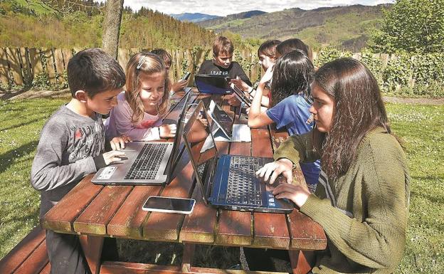 Un grupo de niños del barrio tolosarra de Bedaio trabaja con sus ordenadores portátiles en una mesa situada en el parque, donde pueden conectarse a internet.