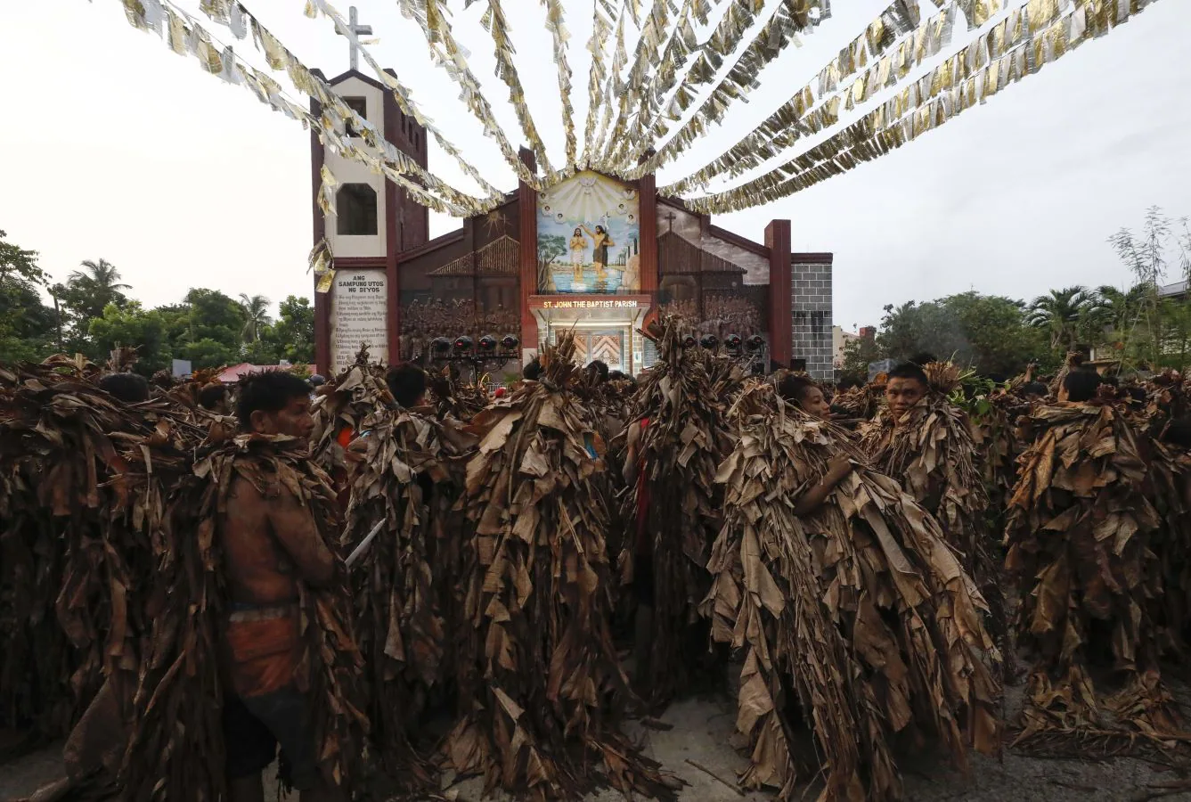 Devotos católicos filipinos de Saint John the Baptist cubiertos de barro y hojas de plátano encienden velas fuera de la Iglesia Parroquial. El ritual de 'Taong Putik' (pueblo de barro) es seguido por una santa misa para conmemorar el día de la fiesta de Saint John the Baptist, mientras los devotos agradecen las oraciones contestadas y esperan una cosecha abundante cada año.