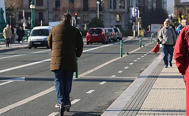 Una persona circula con su patinete eléctrico por un bidegorri. 