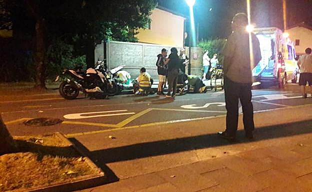 Sanitarios atienden a las dos personas que viajaban en la moto que fue golpeada por el coche que se dio a la fuga. 