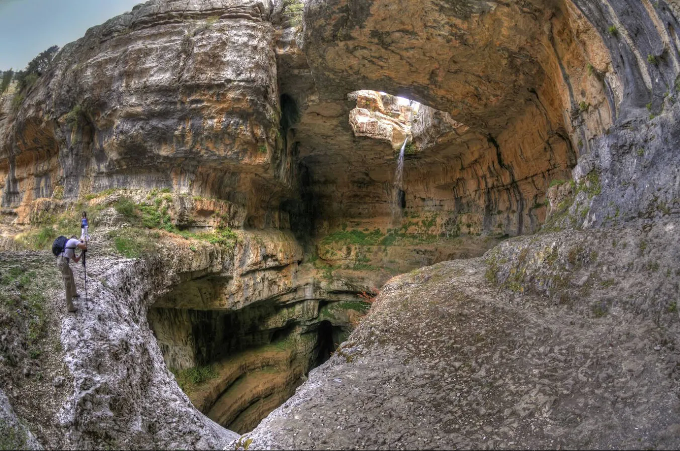 Cascada Baatara Gorge, Líbano. Un pozo vertical de agua helada derretida cae 250 metros a través de una cueva de piedra caliza. A lo largo de los siglos, el agua ha tallado tres arcos de piedra en la cámara principal al final de un desfiladero vertiginosamente empinado. La naturaleza curva de la erosión y la abundancia de vegetación dan la impresión de un paisaje de ensueño.