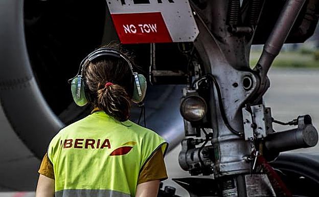 Una trabajadora de Iberia, junto a un avión de la compañía