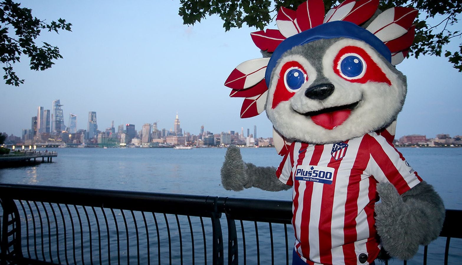 Indi es un mapache disfrazado de indio y con la equipación del Atlético de Madrid. En los años 60 y 70 el Atlético de Madrid realizó muchos fichajes de origen sudamericano. Despectivamente, se les denominó 'indios' por sus rivales.