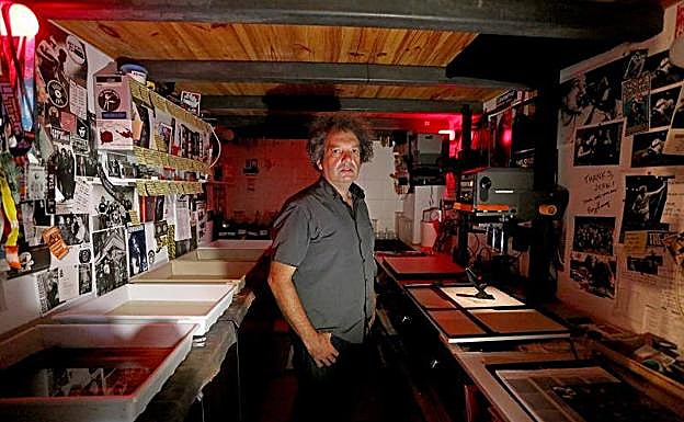 Juxe posa en su laboratorio de Errenteria rodeado de negativos, ampliadoras, cubetas, hojas de contacto y fotografías impresas en papel baritado.