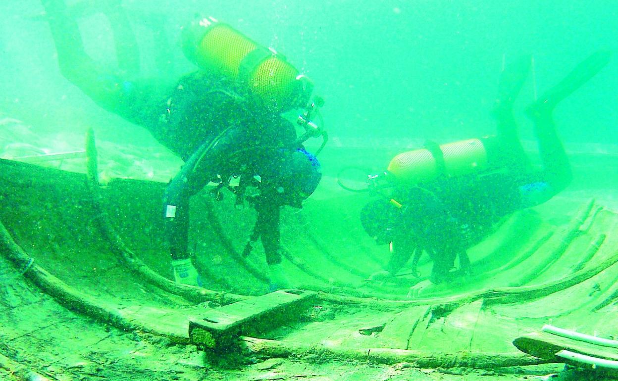 Dos buceadores inspeccionan el casco de la embarcación fenicia.