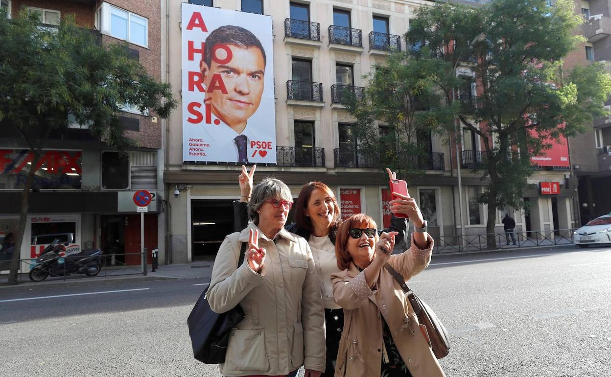 Unas mujeres se hacen un selfie con el cartel electoral del PSOE. 