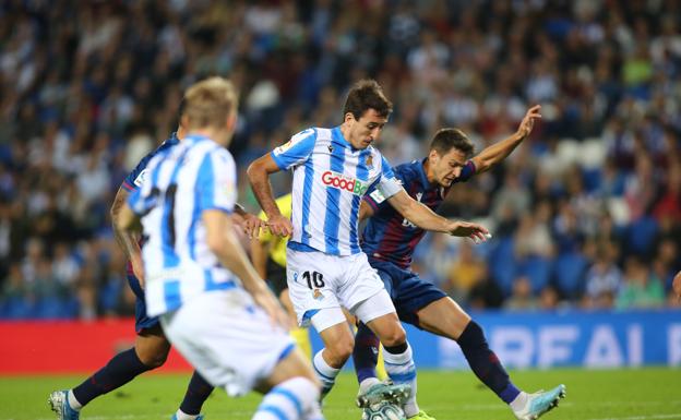 Oyarzabal intenta avanzar con el balón controlado ante el acoso de un jugador del Levante mientras Odegaard sigue de cerca la jugada. 