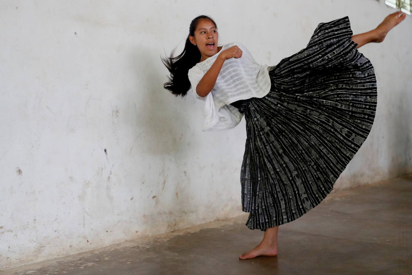Niñas q'qchí de la aldea Tipulcan en San Pedro Carchá practican taekwondo con su maestro, Danny Coy, en una cancha de tierra en el medio de la aldea. Cada golpe es seguido por un fuerte grito que se resuena en las laderas de la zona montañosa de Alta Verapaz, en el norte de Guatemala. Con cada patada al aire, las niñas de la aldea Tipulcan espantan a los fantasmas de la violencia machista y el acoso que han sufrido en su comunidad. 