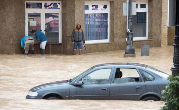 Los vecinos de Los Alcázares (Murcia) tratan de evitar que el agua entre en un comercio.