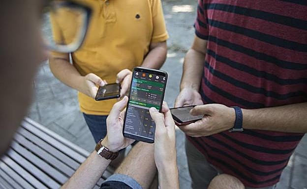 Un grupo de jóvene apuesta desde el teléfono móvil. /