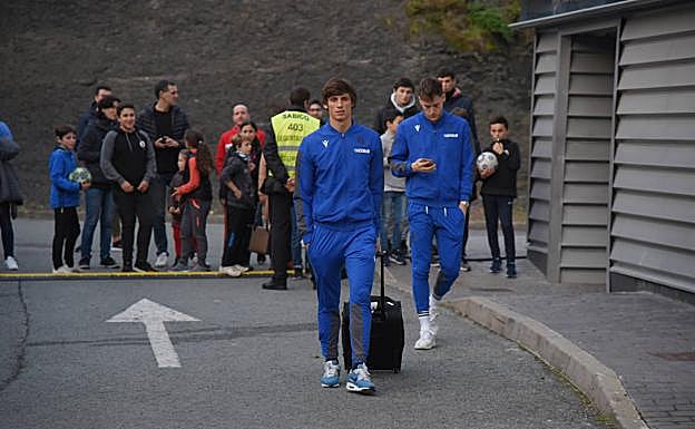 Robin Le Normand y Álex Remiro se dirigen hacia el autobús, observados por varios aficionados que acudieron a Zubieta. 