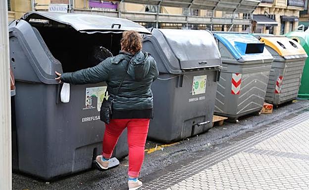Una mujer deposita una bolsa con basura en un contenedor de rechazo situado en el centro de San Sebastián