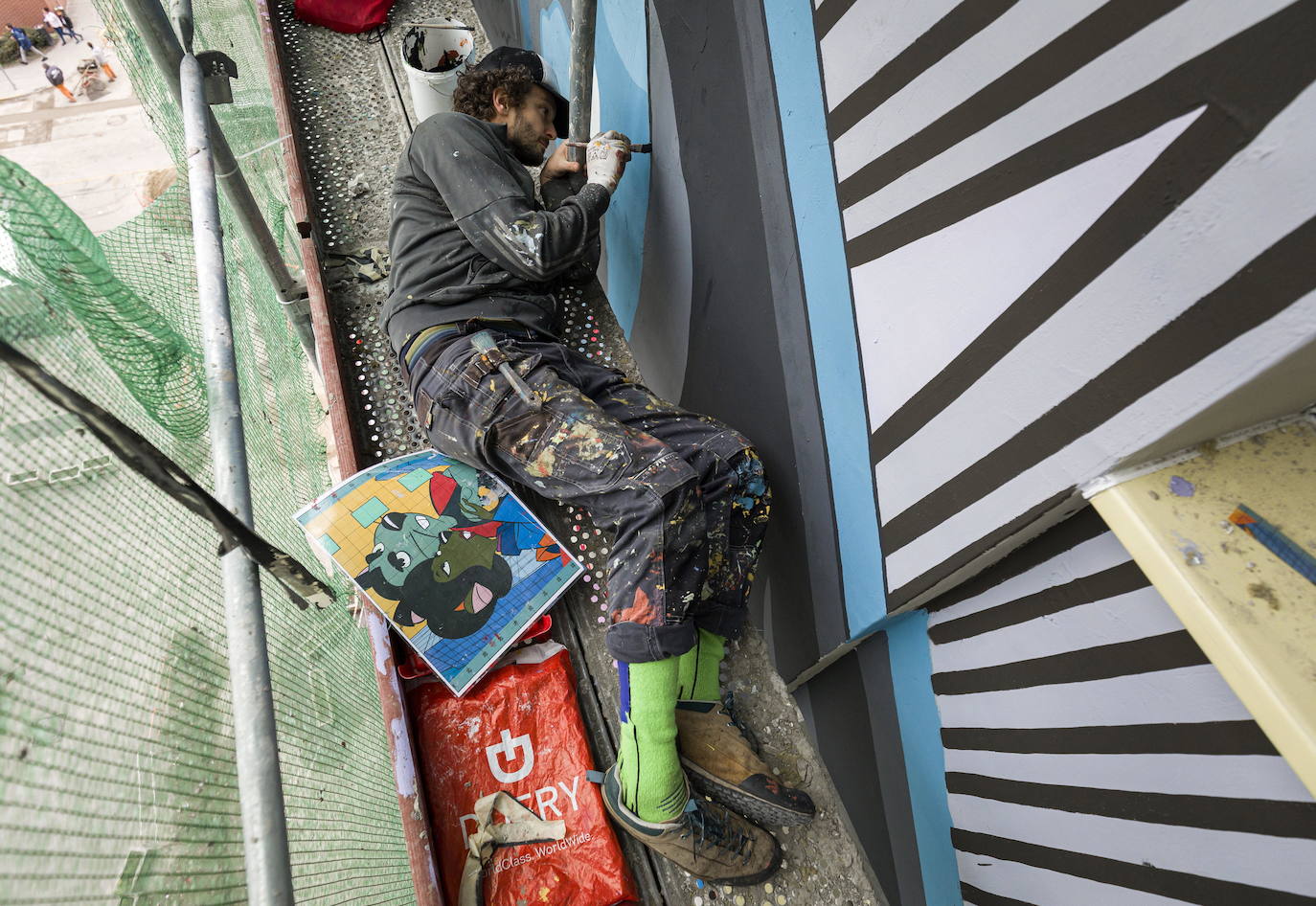 Los miembros del grupo Szines Varos (ciudad colorida) trabajan en un andamio para crear un mural en un edificio residencial en el Distrito VIII de Budapest. La obra de arte de 600 metros cuadrados representa a los personajes principales de la popular caricatura húngara Macskafogo (lit. Cat Catcher) de 1986, que se distribuyó como 'cat city' en Estados Unidos. El colectivo artístico ha realizado muchos murales a gran escala en Budapest y otras ciudades húngaras, así como en Moscú, Berlín y Londres, desde su fundación en 2008.