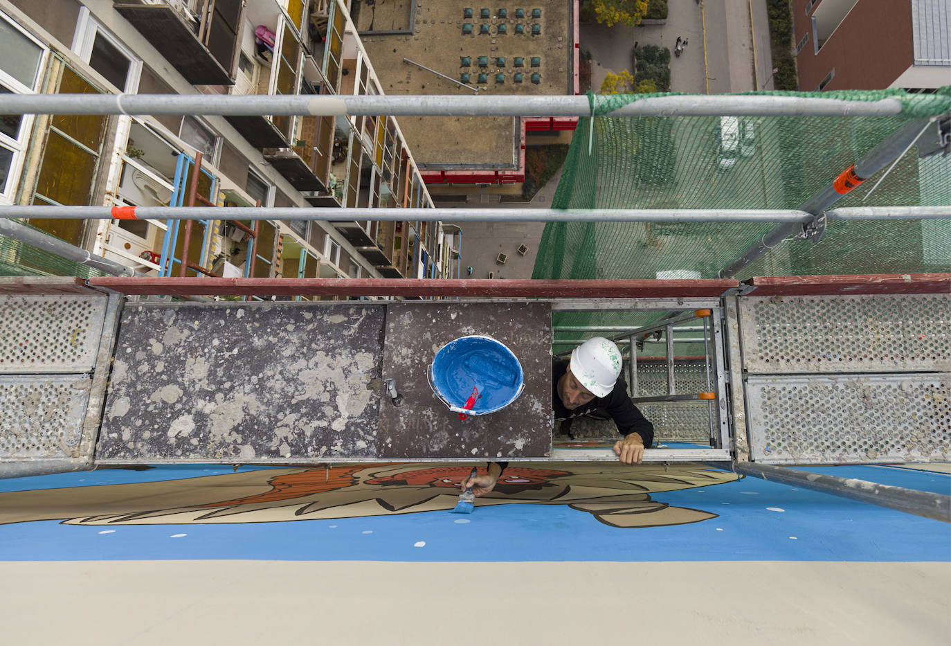 Los miembros del grupo Szines Varos (ciudad colorida) trabajan en un andamio para crear un mural en un edificio residencial en el Distrito VIII de Budapest. La obra de arte de 600 metros cuadrados representa a los personajes principales de la popular caricatura húngara Macskafogo (lit. Cat Catcher) de 1986, que se distribuyó como 'cat city' en Estados Unidos. El colectivo artístico ha realizado muchos murales a gran escala en Budapest y otras ciudades húngaras, así como en Moscú, Berlín y Londres, desde su fundación en 2008.