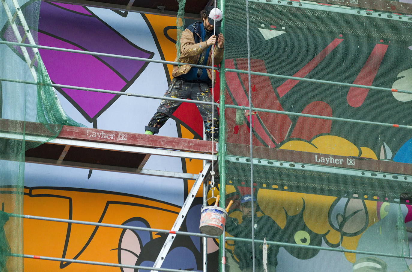Los miembros del grupo Szines Varos (ciudad colorida) trabajan en un andamio para crear un mural en un edificio residencial en el Distrito VIII de Budapest. La obra de arte de 600 metros cuadrados representa a los personajes principales de la popular caricatura húngara Macskafogo (lit. Cat Catcher) de 1986, que se distribuyó como 'cat city' en Estados Unidos. El colectivo artístico ha realizado muchos murales a gran escala en Budapest y otras ciudades húngaras, así como en Moscú, Berlín y Londres, desde su fundación en 2008.