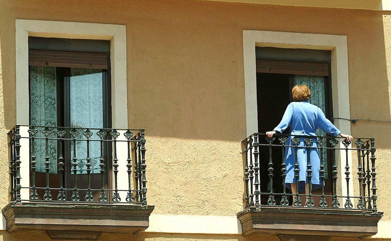 Una mujer se asoma al balcón de su vivienda. 
