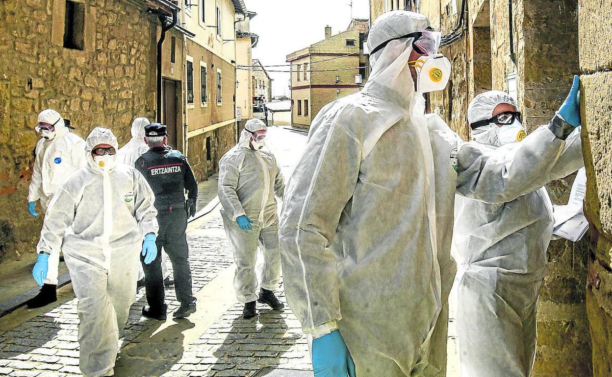 'Beltzas' con el buzo blanco de protección y mascarilla llaman casa por casa a los afectados en Labastida. 