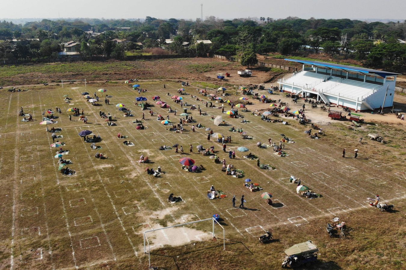 Una localidad de Myanmar ha decido utilizar un campo de fútbol para convertirlo en un gran mercado al aire libre. Sobre el maltrecho césped se han pintado nuevas líneas que ya no dibujan el centro del terreno de juego o las áreas, sino las distancias de seguridad para evitar la propagación del Covid-19.