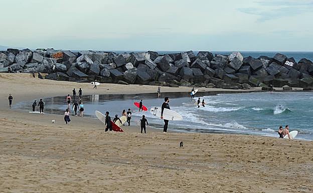Surfistas, bañistas y paseantes, en la playa de La Zurriola a primera hora de la mañana.