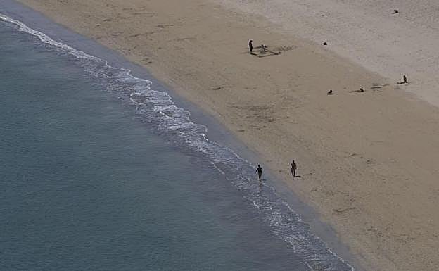 Foto: Hondarribia. Varios paseantes caminan y juegan en la playa, que a partir del lunes permitirá el baño.