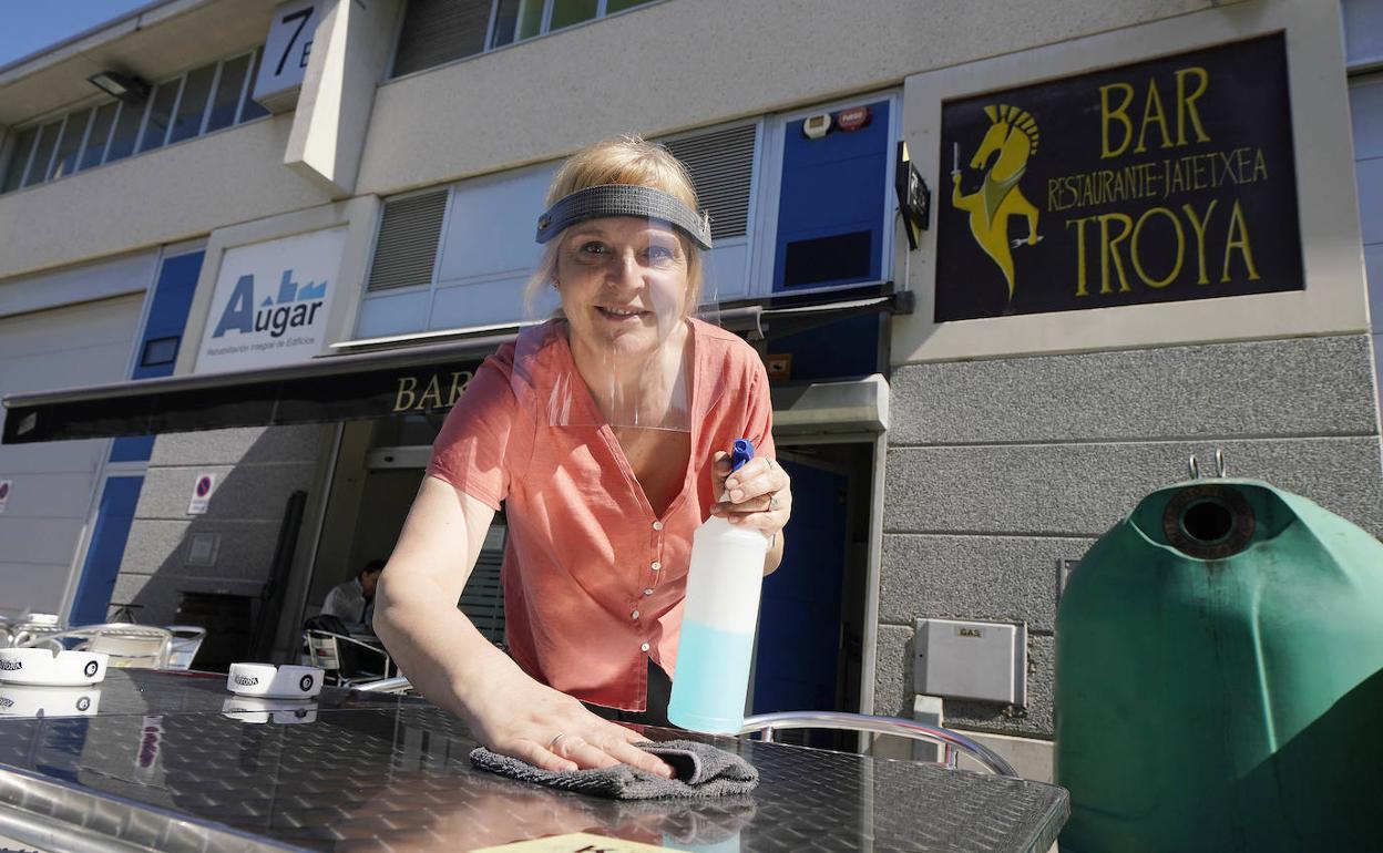 Mertxe Pernas desinfecta tras su uso una de las mesas de la terraza del Troya, un 'bar de polígono' del que está orgullosa.
