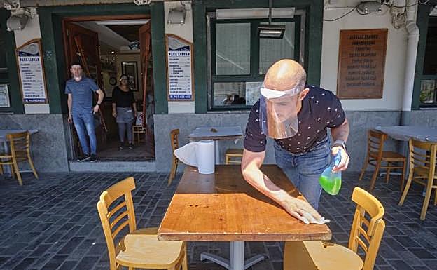 Luis Miguel Herrero desinfecta una de las mesas de La Rampa, en el puerto de Donostia. 