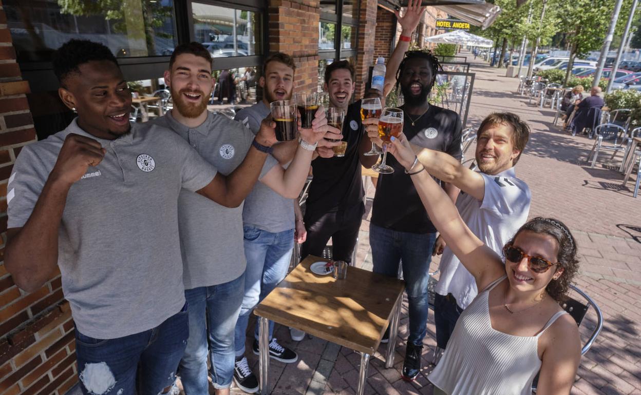 Los jugadores Faye, Olaizola, Mutic, Motos y Jawara, el entrenador ayudante Martínez y la responsable de prensa del club, Eguileta, brindan ayer por el ascenso.