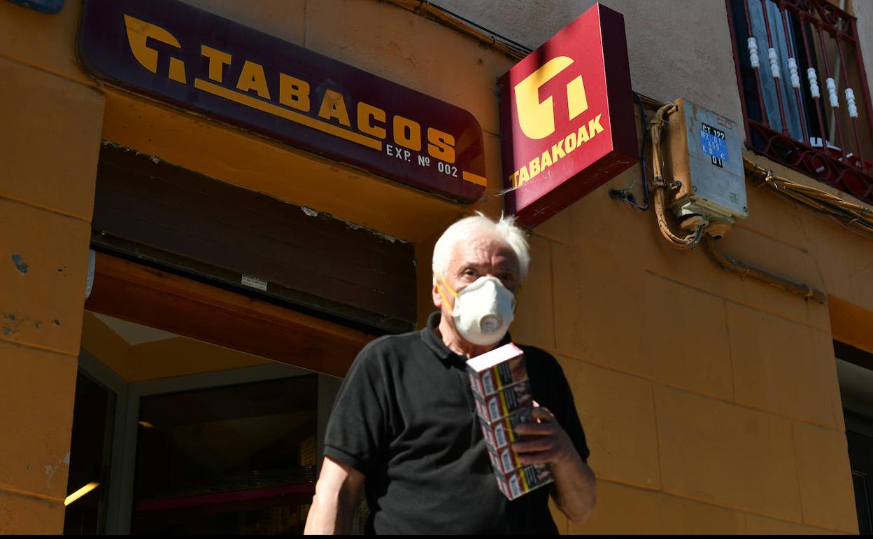 Un hombre sale con un cartón de tabaco de un estanco en Zumaia.