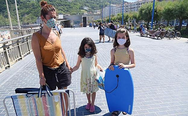 Imagen principal - Josune Areso, sale de la playa de la Zurriola, con sus dos hijas de 10 y 6 años..Jaione Rodríguez no tiene reparo en que su hijo vaya a las colonias, «siempre va con mascarilla». Aitor Idígoras podrá seguir llevando a Juka a las colonias. Al ser privada no tienen la obligación de cerrar.