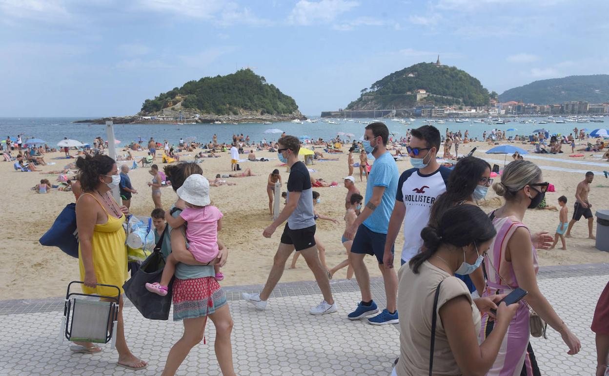 Paseantes junto a la playa de Ondarreta ayer domingo.