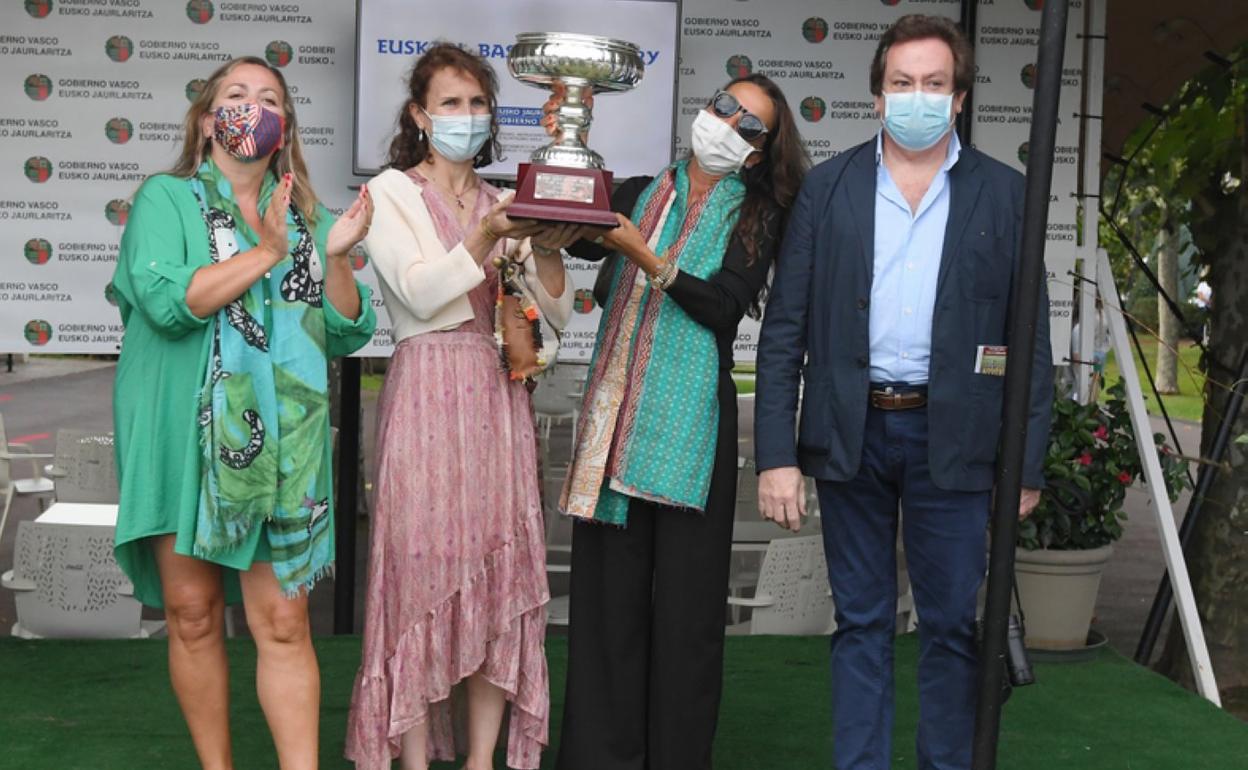 Los propietarios del caballo ganador reciben el trofeo. 