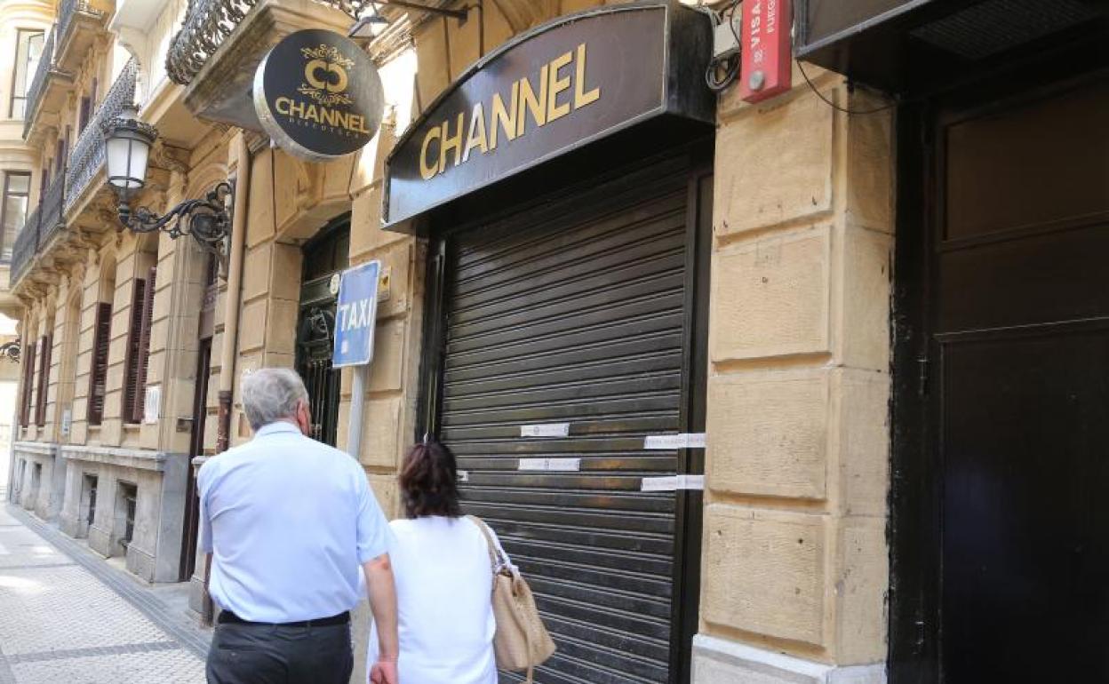 Dos viandantes pasan ante una de las discotecas a cuyos clientes se someterá a las pruebas del Covid. 