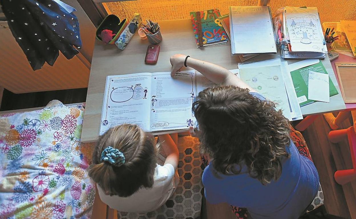 Una madre ayuda a sus hijas a hacer los deberes durante el confinamiento.